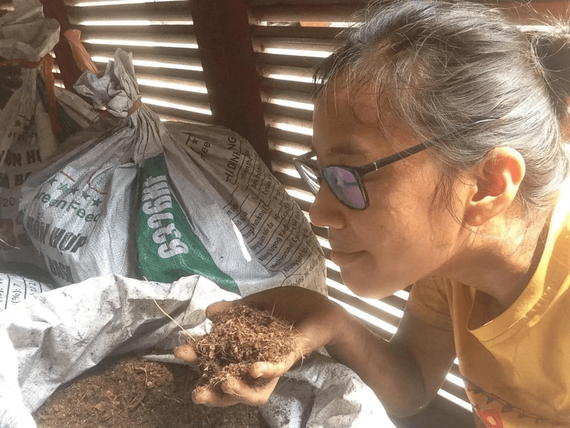Compost City's founder Monorom Tchaw leans over a bag of soil.