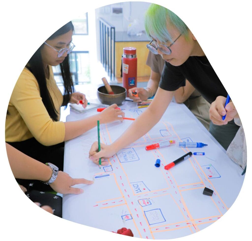 A few staff of Impact Hub Phnom Penh lean over a large piece of paper making a diagram.