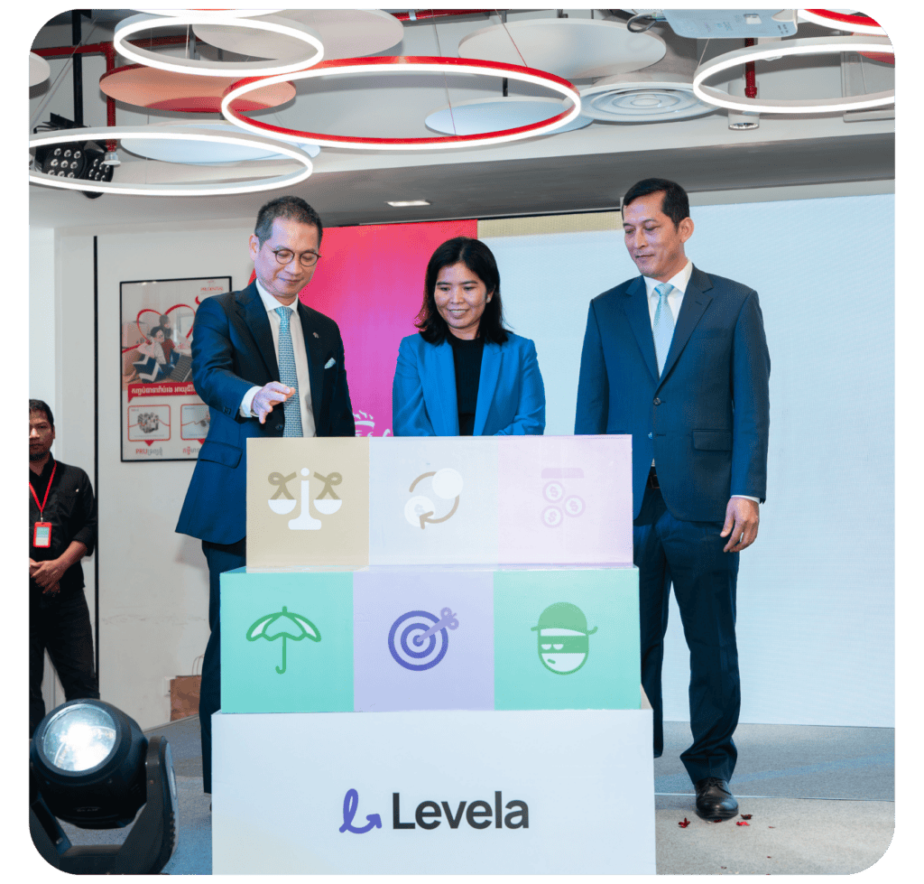 Three people standing in front of a colorful display with various icons, engaged in a presentation or unveiling at a corporate event.