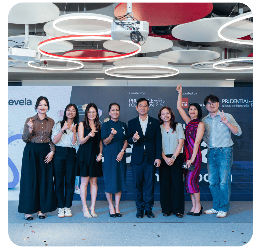 A group of eight individuals standing together in a modern office space, smiling and posing for the camera, with a backdrop featuring company logos.
